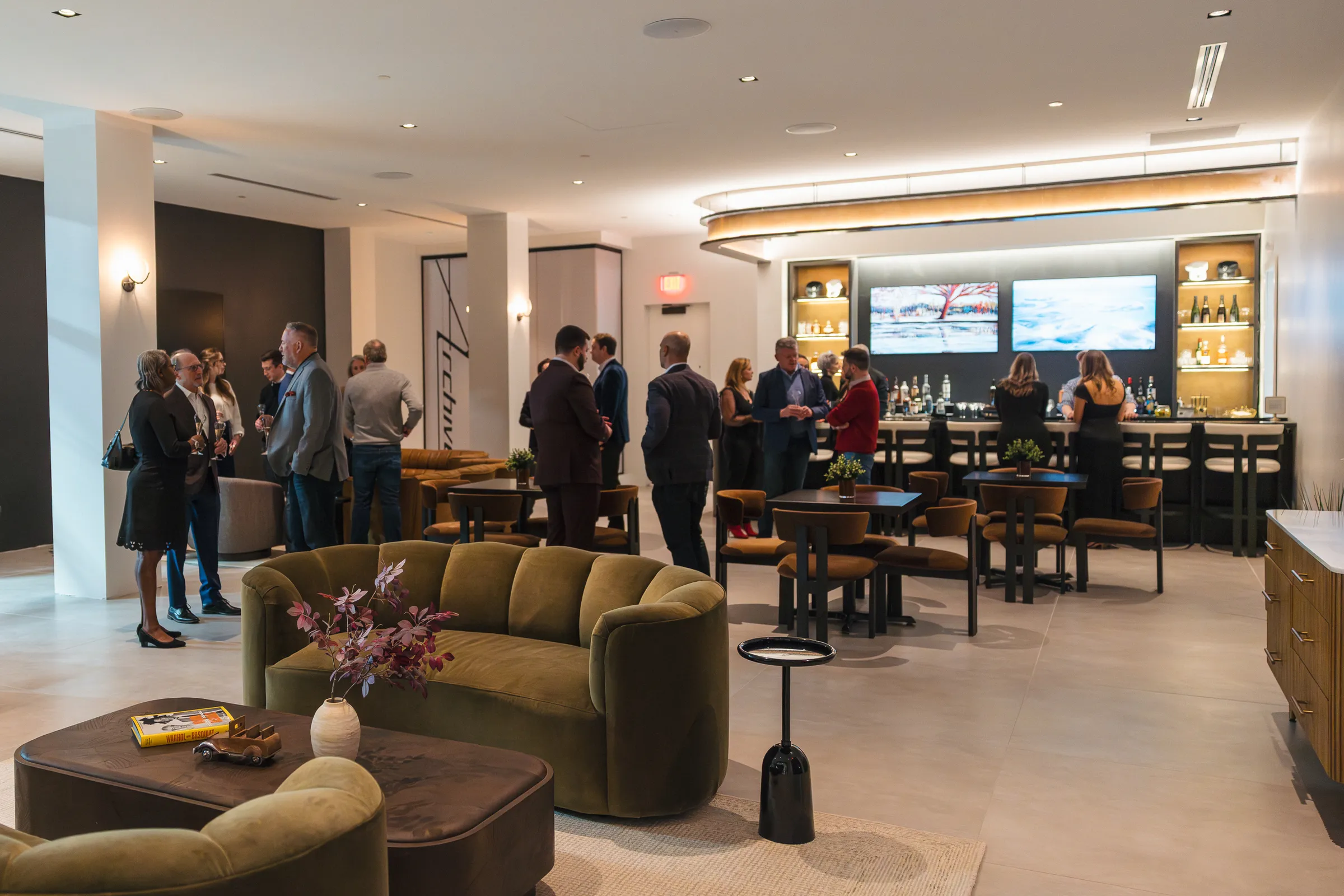 Members mingling through a full Archive lounge at an evening event, the bar and collection beyond