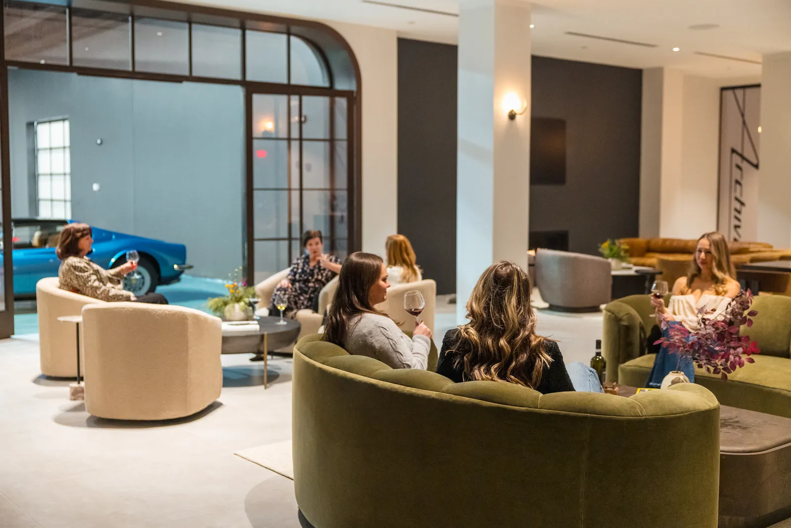 Members sharing wine in the Archive lounge, with the collection visible through the gallery glass