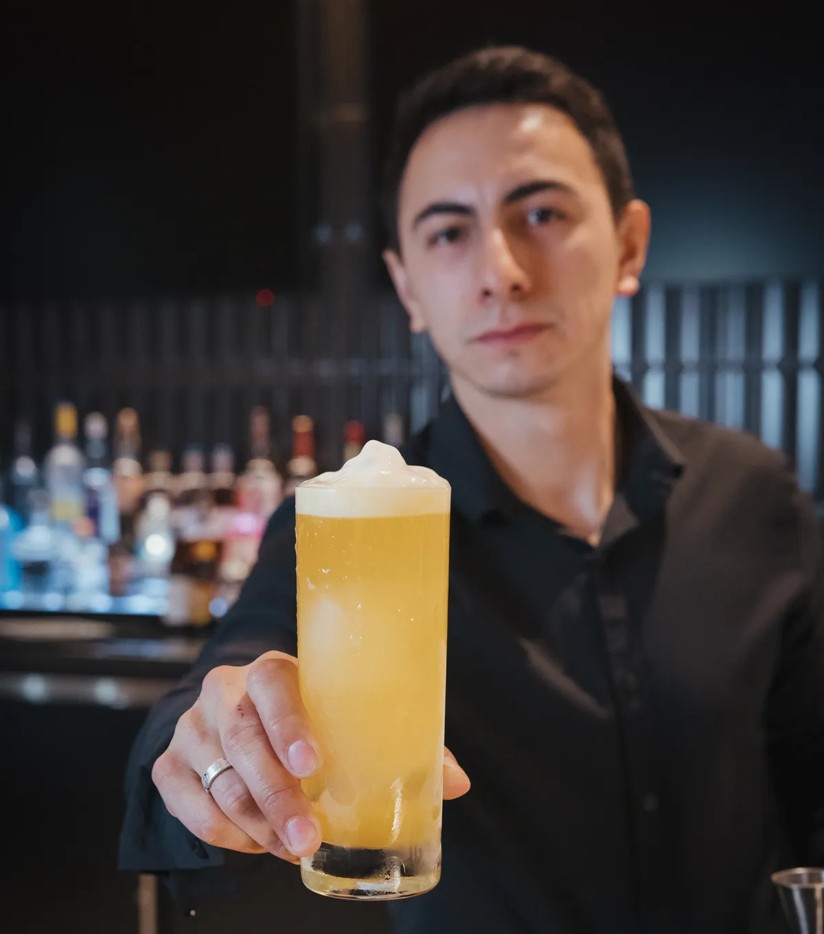 Archive's bartender presenting a signature cocktail at the bar