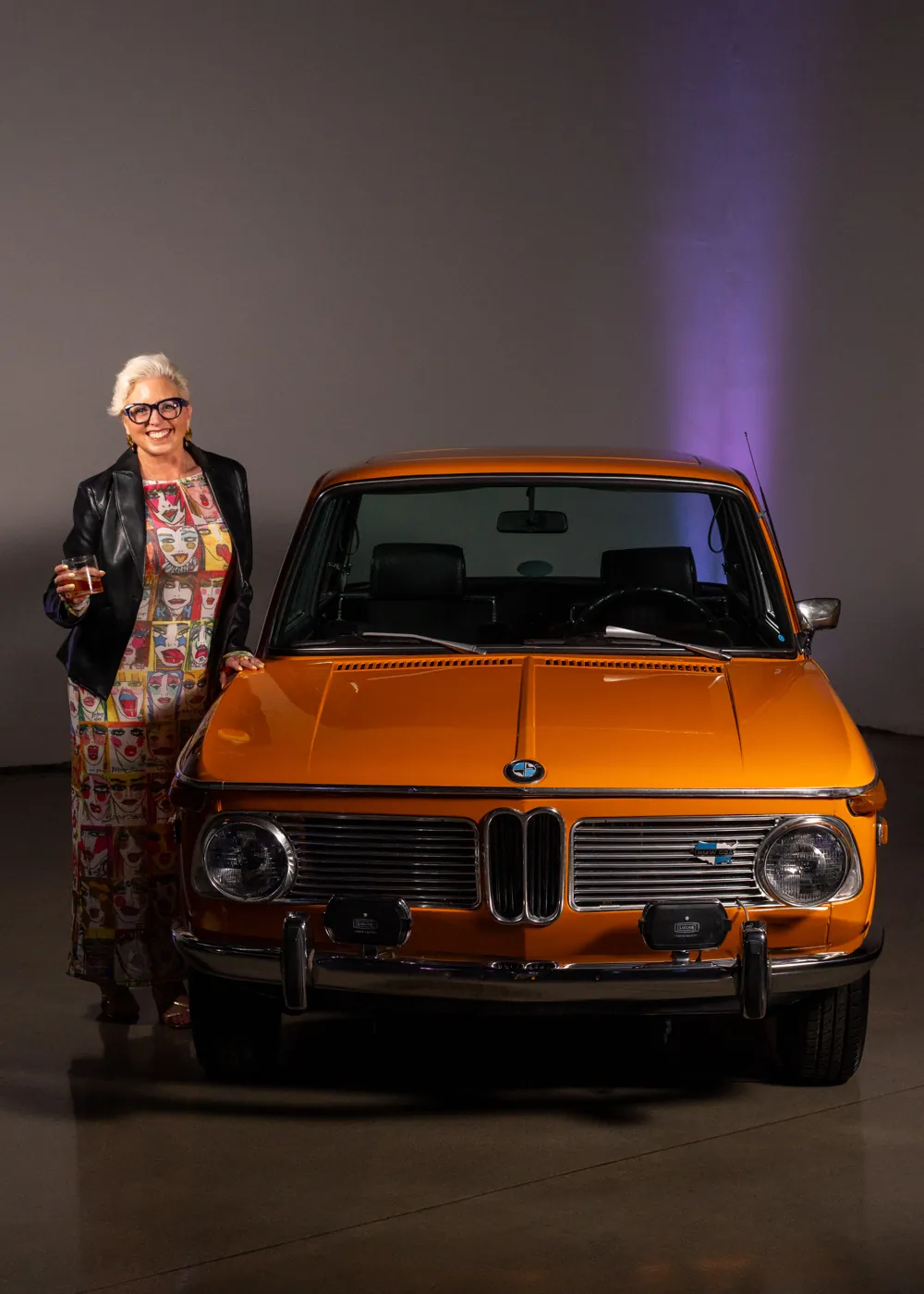 A guest with a glass beside a classic BMW at a Driven by Taste event