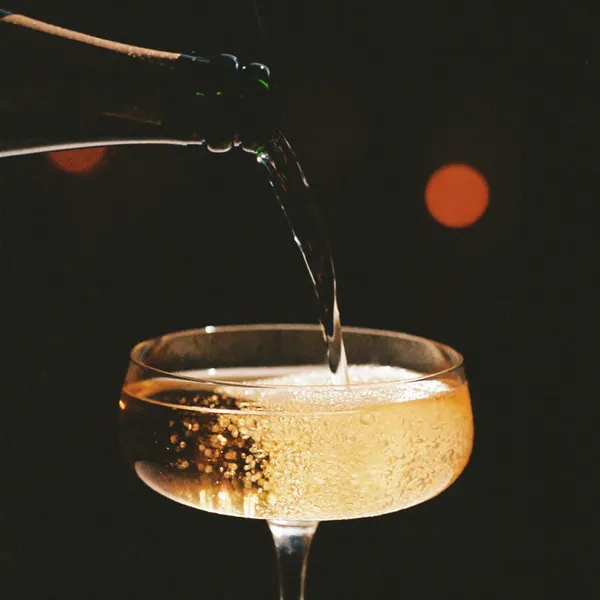 A champagne pour with soft sparkler bokeh in the dark