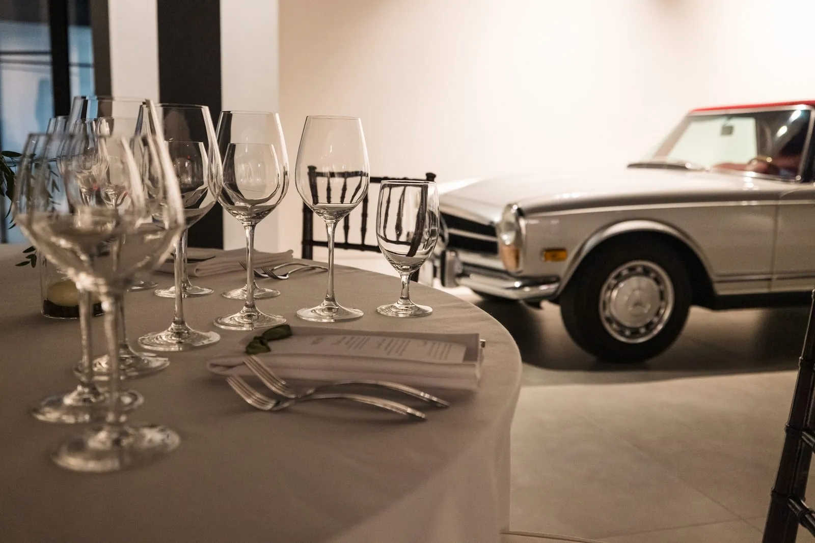 A wine dinner table set beside a classic Mercedes in the Archive showroom